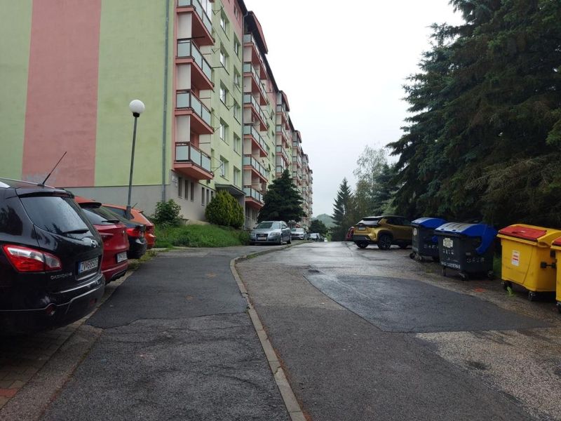 Predaj investičného pozemku. Podborová - Pohľad na bytovku a parkovisko na Ružovej ulici v Zvolene, obklopené stromami.