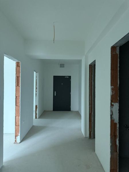 Nové skolaudované byty a nebytové priestory. Výhodné ceny. - Svetlá chodba v 2-izbovom byte s bielymi stenami a betónovou podlahou.