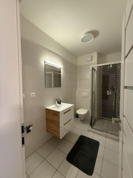 Nové skolaudované byty a apartmány vo Vajnoroch. - Kúpeľňa so sprchovým kútom, umývadlom a zrkadlom, 2-izbový byt s dlažbou.