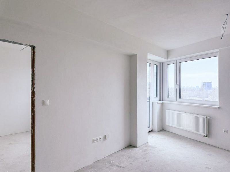 Nové skolaudované byty a apartmány vo Vajnoroch. - Svetlá miestnosť s veľkými oknami v 3-izbovom byte bez podlahových krytín.