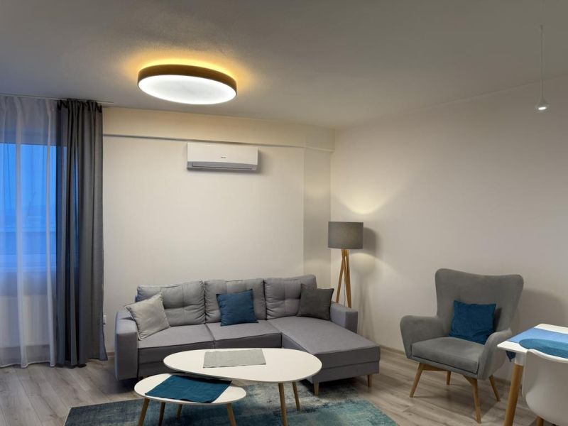 Nové skolaudované byty a apartmány v projekte Diamant. - Obývacia izba s pohovkou, kreslom a stolíkom v 2-izbovom byte s dekorom podlahy.