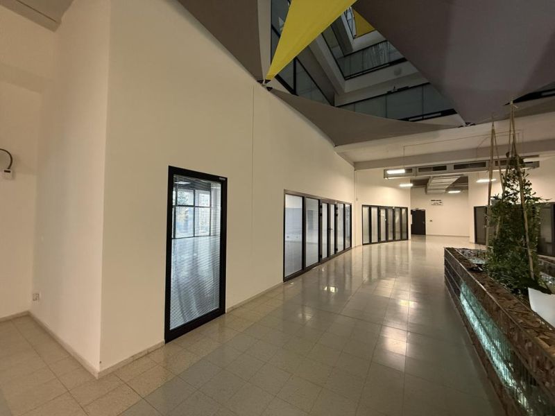 Nové skolaudované byty a apartmány v projekte Diamant. - Interiér administratívnej budovy s presklenými kanceláriami, dlažba na podlahe a zeleňou.
