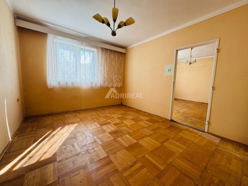 PREDAJ: 2i byt; 65 m2; CENTRUM - KRUPINA; 84.500 €  - Izba v 2-izbovom byte s podlahou s dreveným dekorom a závesmi na okne.