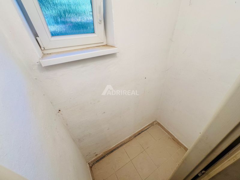 PREDAJ: 2i byt; 65 m2; CENTRUM - KRUPINA; 84.500 €  - Malá miestnosť s oknom, bielymi stenami a svetlou dlažbou v 2-izbovom byte.