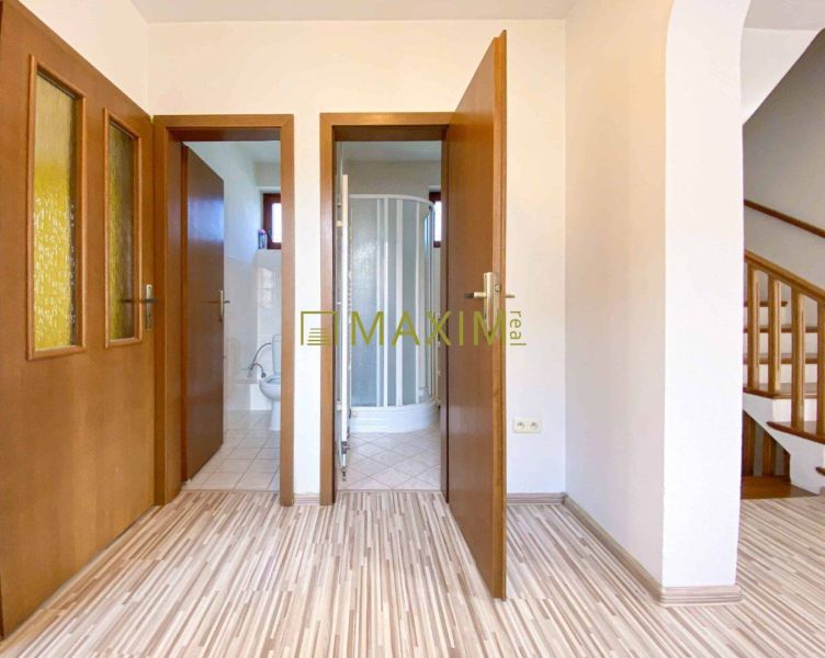 5-izbový rodinný dom, dvojpodlažný, podpivničený, Kátlovce - Chodba v rodinnom dome s podlahou s dreveným dekorom, kúpeľňa a schodisko.