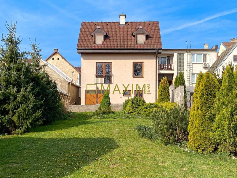 5-izbový rodinný dom, dvojpodlažný, podpivničený, Kátlovce - Rodinný dom v Kátlovciach so záhradou, obklopený zeleňou a modrou oblohou.