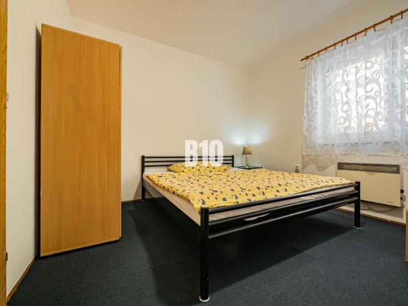 APARTMÁNOVÝ DOM v Radave - 7 apartmánov na predaj - Spálňa v rodinnom dome s kovovou posteľou, skriňou a vzorovanou záclonou.