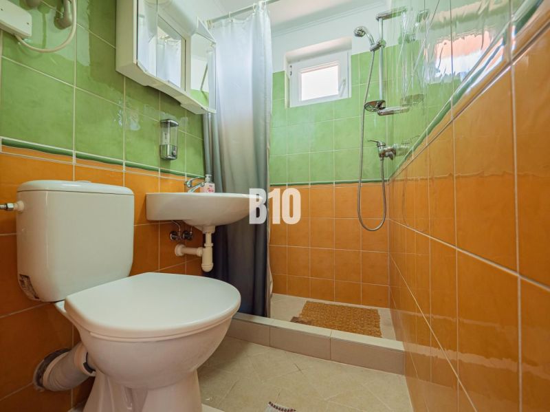 APARTMÁNOVÝ DOM v Radave - 7 apartmánov na predaj - Kúpeľňa v rodinnom dome s oranžovo-zelenými obkladmi a sprchovacím kútom.