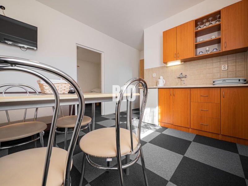 APARTMÁNOVÝ DOM v Radave - 7 apartmánov na predaj - Kuchyňa v rodinnom dome s tmavou dlažbou a drevenými skrinkami.
