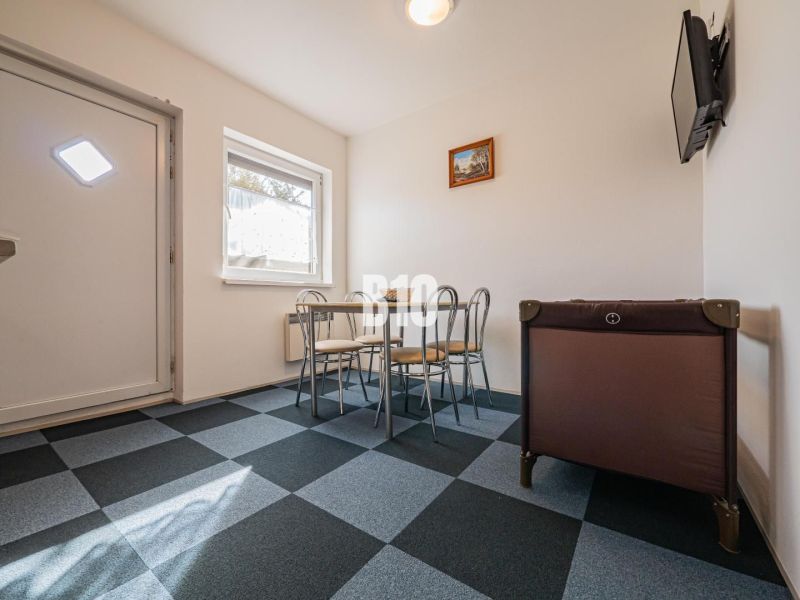 APARTMÁNOVÝ DOM v Radave - 7 apartmánov na predaj - Jedálenský kút v rodinnom dome s geometrickou podlahou a detskou postieľkou.