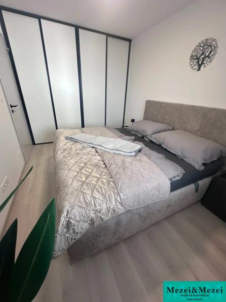 Prenájom 2 izbového bytu ARBORIA Trnava - Spálňa v 2-izbovom byte s posteľou, šatníkovou skriňou a podlahou s dreveným dekorom.