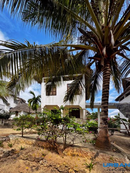 SAMOSTATNE STOJACA VILA MAPUMZIKO S 2 IZBAMI NA ZANZIBARE  - Rodinný dom v Pwani Mchangani obklopený palmami a kvetmi na kamennej terase.