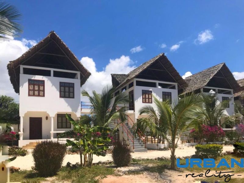 SAMOSTATNE STOJACA VILA MAPUMZIKO S 2 IZBAMI NA ZANZIBARE  - Rodinný dom v Fumba Town s palmovými stromami a trstinovou strechou pod modrou oblohou.