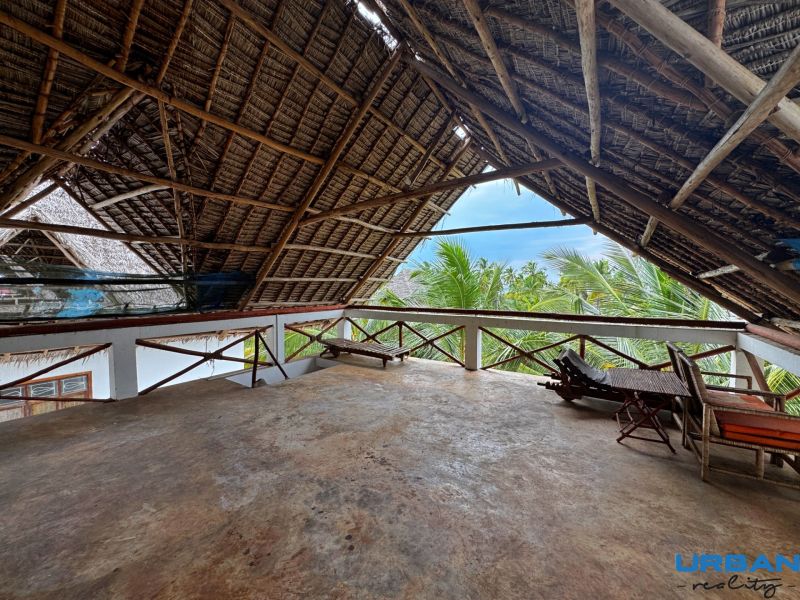 SAMOSTATNE STOJACA VILA MAPUMZIKO S 2 IZBAMI NA ZANZIBARE  - Rustikálna strecha na poschodí rodinného domu v Fumba Town s výhľadom na palmy.