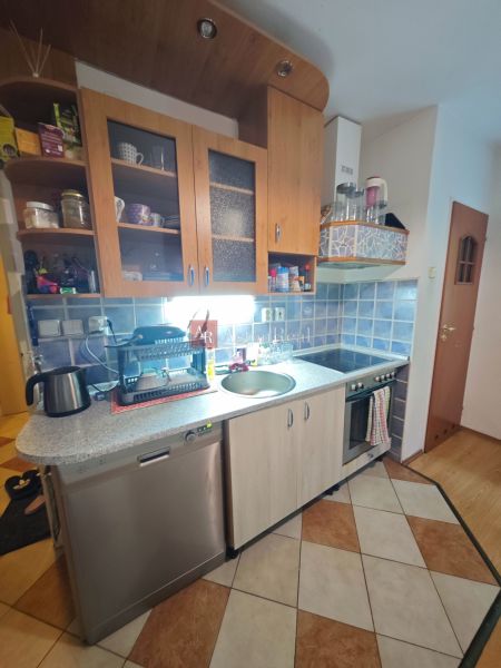 PREDAJ 2-izbový byt Harmanec 56 m2 s balkónom  - Kuchyňa v 2-izbovom byte s modrými kachličkami a podlahou s dreveným dekorom.