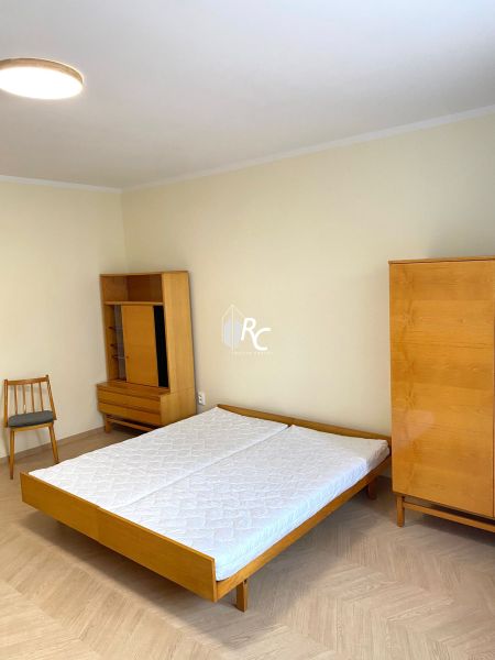 Prenájom 2-izbového bytu, Martin - centrum - Spálňa s posteľou, skriňou a podlahou s dreveným dekorom v 3-izbovom byte.