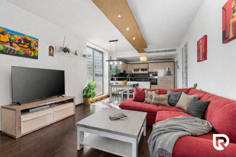 Apartmán vhodný na Airbnb aj rodinné bývanie | Vienna Gate - Obývacia izba s červeným rohovým gaučom, televízorom a kuchynským kútom v 3-izbovom byte.