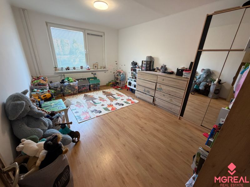 3 izbový byt s balkónom Topoľčany  - Detská izba s hračkami a podlahou s dreveným dekorom v 3-izbovom byte.