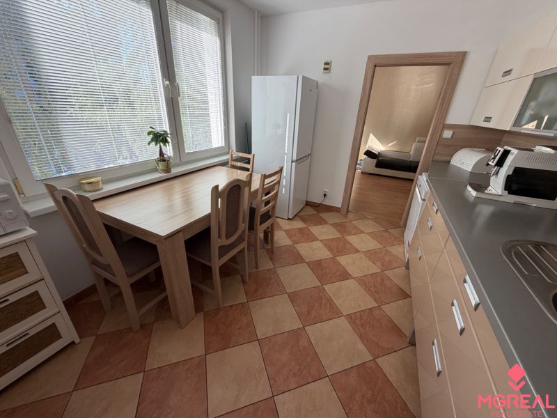 3 izbový byt s balkónom Topoľčany  - Kuchyňa v 3-izbovom byte s kachličkovou podlahou, jedálenským stolom a spotrebičmi.