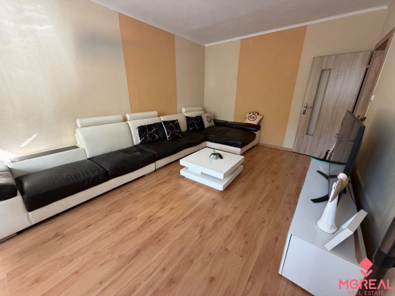 3 izbový byt s balkónom Topoľčany  - Obývacia izba s pohovkou, televíziou a podlahou s dreveným dekorom v 3-izbovom byte.