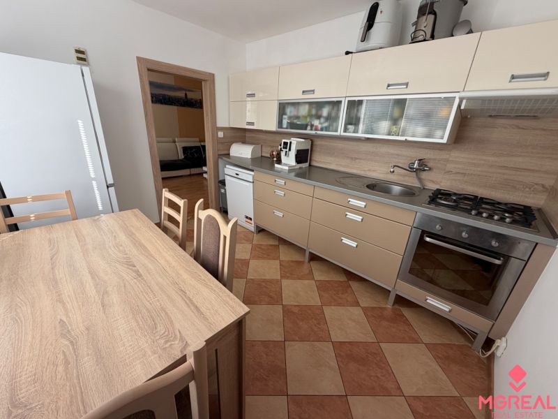 3 izbový byt s balkónom Topoľčany  - Kuchyňa 3-izbového bytu s rohovou linkou, jedálenským stolom a spotrebičmi.