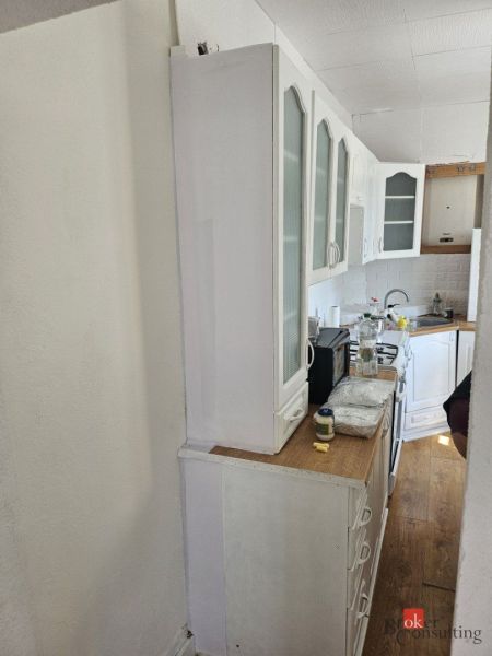 EXKLUZÍVNE NA PREDAJ 2-izbový rodinný dom v širšom centre Nitry s pote - Kuchyňa v rodinnom dome s bielym nábytkom a podlahou s dreveným dekorom.