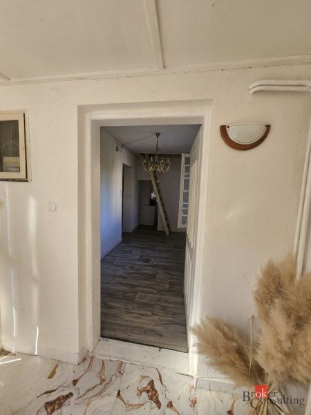 EXKLUZÍVNE NA PREDAJ 2-izbový rodinný dom v širšom centre Nitry s pote - Obývacia izba s televíziou, skriňou, oknom a podlahou s dreveným dekorom v rodinnom dome.