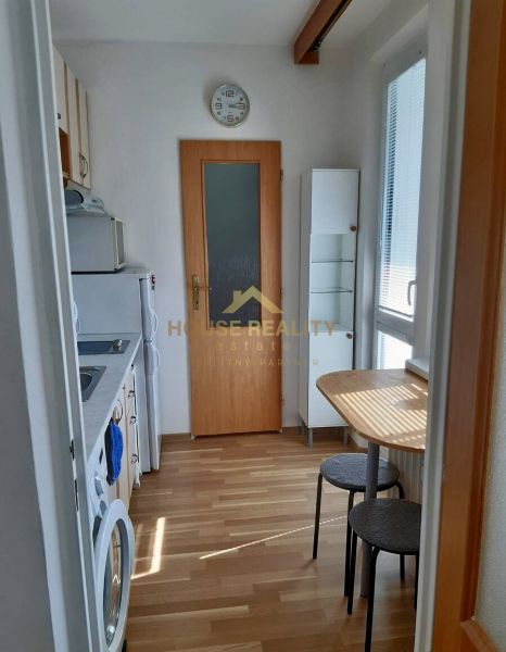 Prenájom 1 izbový byt, ulica Donnerova, Bratislava IV. Karlova Ves - Kuchyňa v 1-izbovom byte so spotrebičmi a podlahou s dreveným dekorom.
