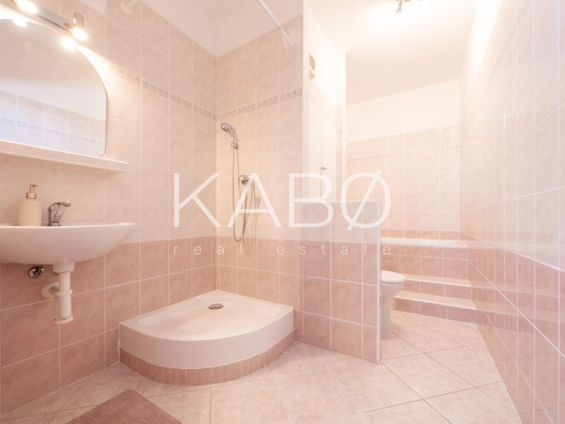 Klimatizácia | Výhľad na Zobor | Balkón a Komfortná veľkosť - Kúpeľňa s dlažbou a sprchovacím kútom v 2-izbovom byte s jemnými odtieňmi béžovej.