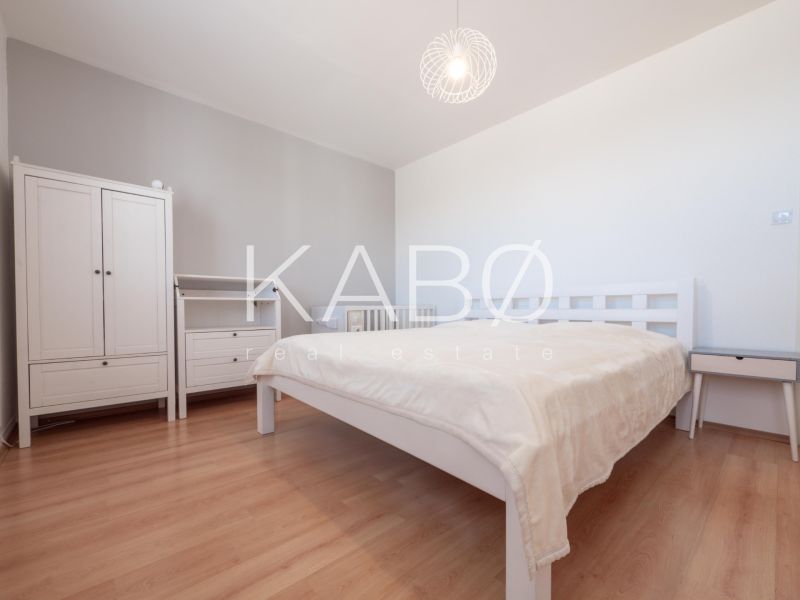 Klimatizácia | Výhľad na Zobor | Balkón a Komfortná veľkosť - Spálňa v 2-izbovom byte s podlahou s dreveným dekorom, svetlým nábytkom a lampou.