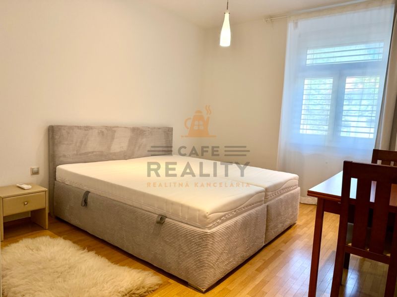 Na prenájom 2 izbový byt, 65 m2, Bratislava, centrum, Vajanského nábr. - Spálňa v 2-izbovom byte s posteľou, nočným stolíkom a drevenou podlahou.