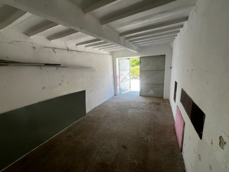 Ponúkame na predaj garáž, Vyhnianska cesta, Bratislava - Nové Mesto. - Interiér garáže s betónovou podlahou a otvorenými plechovými dverami.