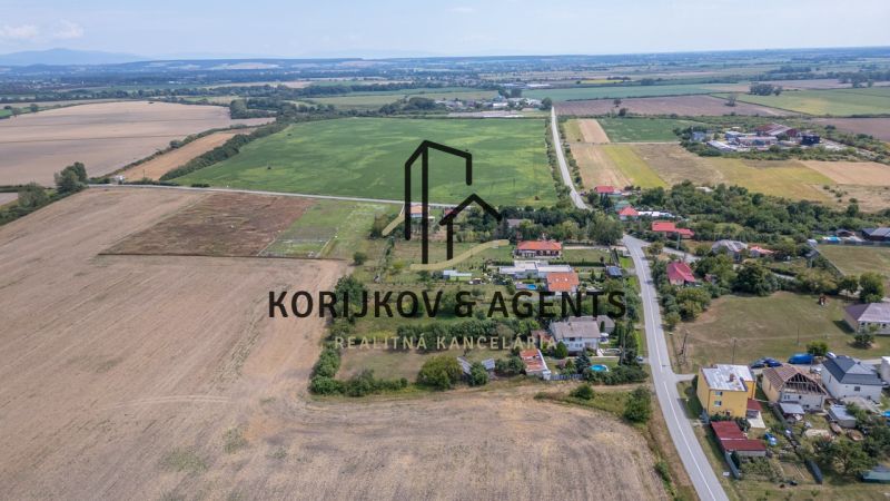 PREDAJ, Stavebný pozemok Sečovce - časť Albinov, intravilan  - Letecký pohľad na pozemky pre bývanie v Sečovciach, obklopené poľom a dedinskou zástavbou.