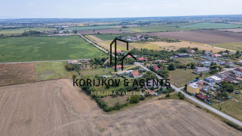 PREDAJ, Stavebný pozemok Sečovce - časť Albinov, intravilan  - Letecký pohľad na pozemky určené na bývanie v Sečovciach, obklopené poliami a domami.