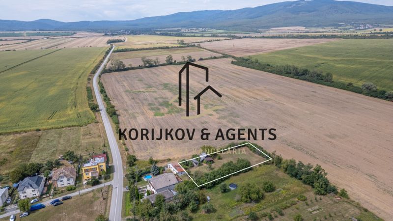 PREDAJ, Stavebný pozemok Sečovce - časť Albinov, intravilan  - Krajina v Sečovciach s rozľahlými pozemkami pre bývanie, obklopená poľami a cestou.