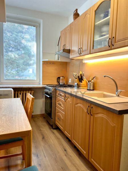 Na predaj 2 izbový byt, 47 m2, Bratislava, Nové Mesto, Piešťanská ul. - Kuchyňa v 2-izbovom byte s dreveným nábytkom a podlahou s dreveným dekorom.