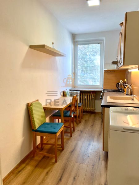 Na predaj 2 izbový byt, 47 m2, Bratislava, Nové Mesto, Piešťanská ul. - Kuchyňa s dvoma stoličkami a podlahou s dreveným dekorom v 2-izbovom byte.