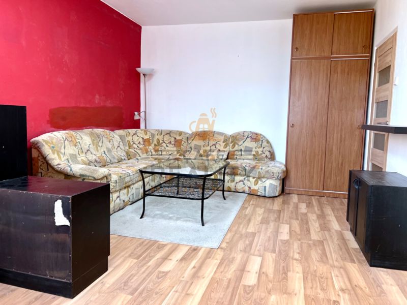 Na predaj 2 izbový byt, 47 m2, Bratislava, Nové Mesto, Piešťanská ul. - Obývacia izba s pohovkou, skriňou a podlahou s dreveným dekorom v 2-izbovom byte.