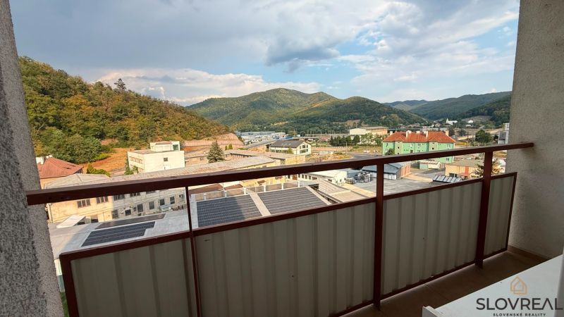 Priestranný veľkometrážny 4-izbový byt v Novej Bani - Výhľad z balkóna 4-izbového bytu v Novej Bani na hory a budovy.