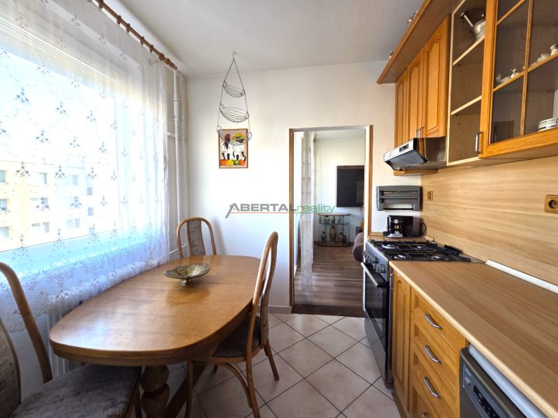 PRENÁJOM 3-izb.byt /loggia/ klíma/ Dudvážska–BA Podunajské Biskupice - Kuchyňa v 3-izbovom byte s jedálenským stolom, dlažbou a dreveným dekorom.