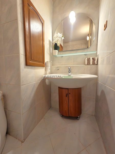 PRENÁJOM 3-izb.byt /loggia/ klíma/ Dudvážska–BA Podunajské Biskupice - Kúpeľňa v 3-izbovom byte so zrkadlom, umývadlom a skrinkou s dreveným dekorom.