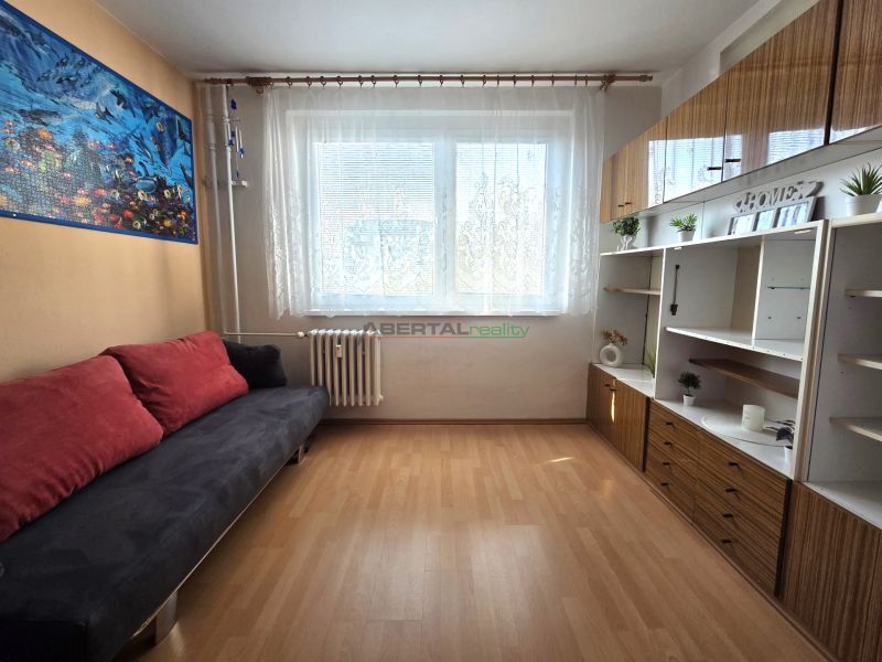 PRENÁJOM 3-izb.byt /loggia/ klíma/ Dudvážska–BA Podunajské Biskupice - Obývacia izba s pohovkou, skrinkami a podlahou s dreveným dekorom v 3-izbovom byte.