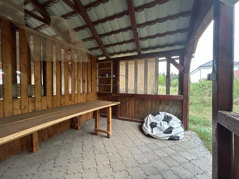 Na predaj 2 izbový byt 54 m2 po rekonštrukcii + záhrada, obec Telince - Drevený prístrešok v Telinciach a 2-izbový byt s kamennou podlahou v pozadí.