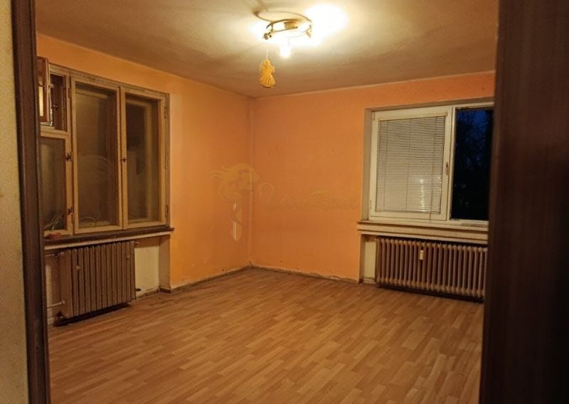 Veľký 2-izb. byt, Olbrachtova ul., Nové Mesto - Izba v 2-izbovom byte, oranžové steny, podlaha s dreveným dekorom, radiátory.