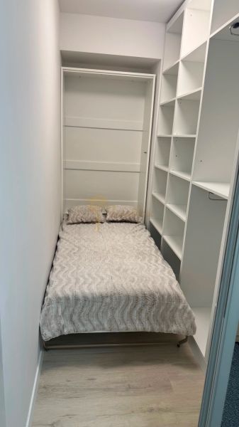 Novostavba 2,5-izb. bytu v NUPPU, garážové státie + vonkajšie státie - Úzka spálňa v 2-izbovom byte s posteľou a otvorenými policami.