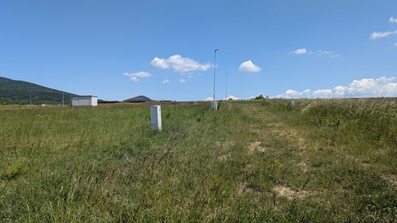 Stavebný pozemok 681 m2 v Štitároch  - Pozemky - bývanie na Zamoyského v Štitároch s trávnatým porastom, lampami a kopcom v pozadí.