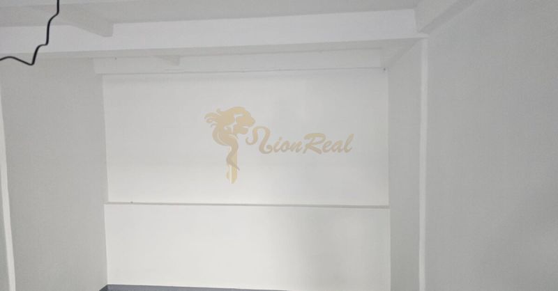 Garáž v radovej zástavbe, Karloveská ul., BA IV - Karlova Ves - Biela stena v Garáži s logom LionReal a certifikátom overenej realitnej kancelárie.