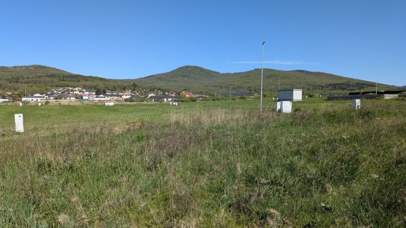 Stavebný pozemok v Štitároch 764 m2 s výhľadom na Nitru - Pozemky - bývanie v Štitároch, zelená krajina s výhľadom na kopce a dedinu.