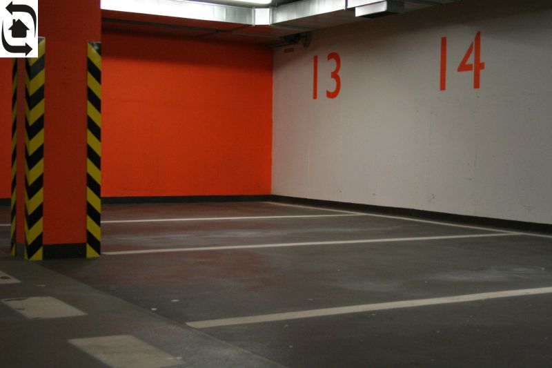Prenájom parkovacieho miesta v podzemnej garáži v centre Bratislavy - Parkovacie miesta a oranžová stena v garáži so žltými a čiernymi stĺpmi.