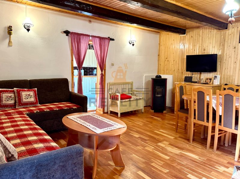 Na predaj chalupa, pozemok 1891 m2, obec Šumiac, okr. Brezno - Obývacia izba s krbom, televíziou a podlahou s dreveným dekorom v rodinnom dome.